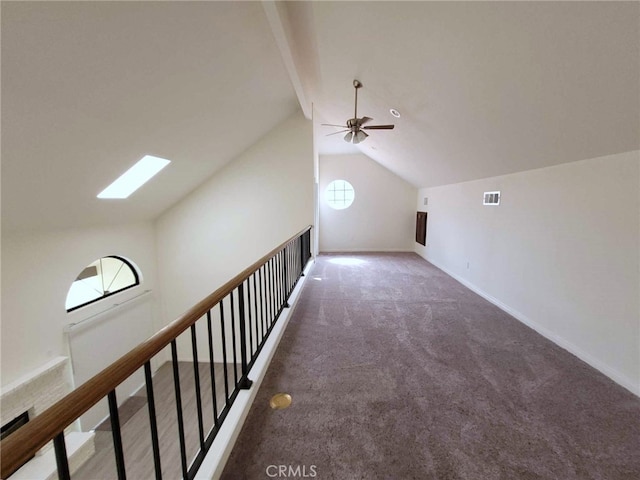 additional living space with ceiling fan, dark colored carpet, and lofted ceiling with skylight