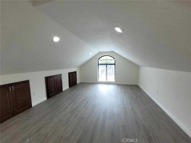 bonus room with lofted ceiling and dark wood-type flooring