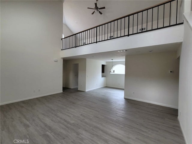 unfurnished living room with ceiling fan, hardwood / wood-style floors, and high vaulted ceiling