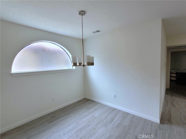 unfurnished dining area featuring a chandelier and light hardwood / wood-style flooring