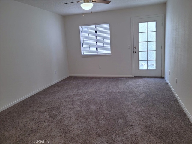 spare room featuring dark carpet, a textured ceiling, and ceiling fan