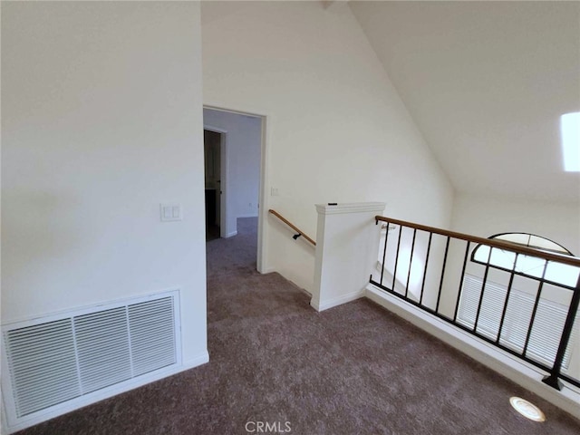 hall featuring high vaulted ceiling and dark colored carpet