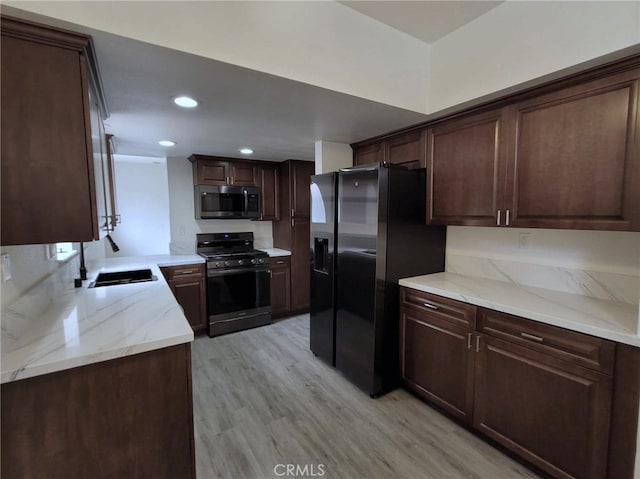 kitchen with black appliances, light stone countertops, sink, light hardwood / wood-style flooring, and dark brown cabinets