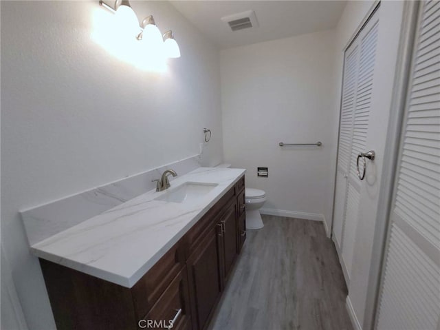 bathroom featuring wood-type flooring, vanity, and toilet