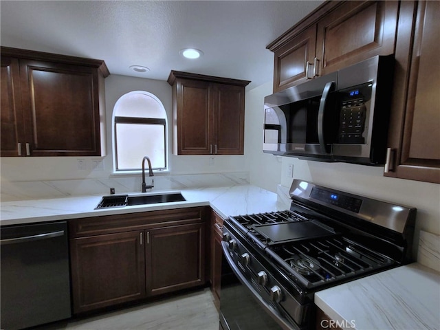 kitchen featuring dark brown cabinets, appliances with stainless steel finishes, light wood-type flooring, and sink