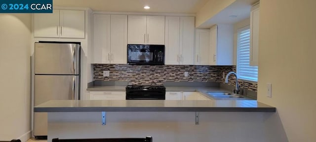 kitchen featuring white cabinetry, tasteful backsplash, black appliances, and sink