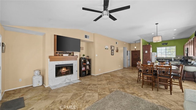 dining space with vaulted ceiling, ceiling fan, and a premium fireplace