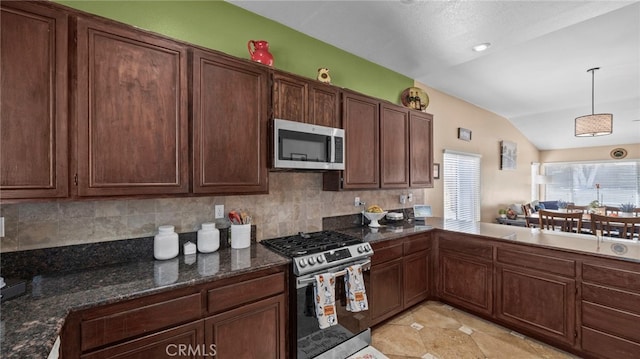 kitchen with dark stone counters, lofted ceiling, hanging light fixtures, stainless steel appliances, and backsplash