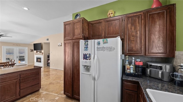 kitchen featuring vaulted ceiling, white refrigerator with ice dispenser, tasteful backsplash, ceiling fan, and dark brown cabinetry