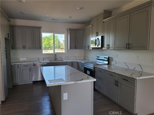 kitchen featuring appliances with stainless steel finishes, a center island, dark wood-type flooring, and gray cabinetry