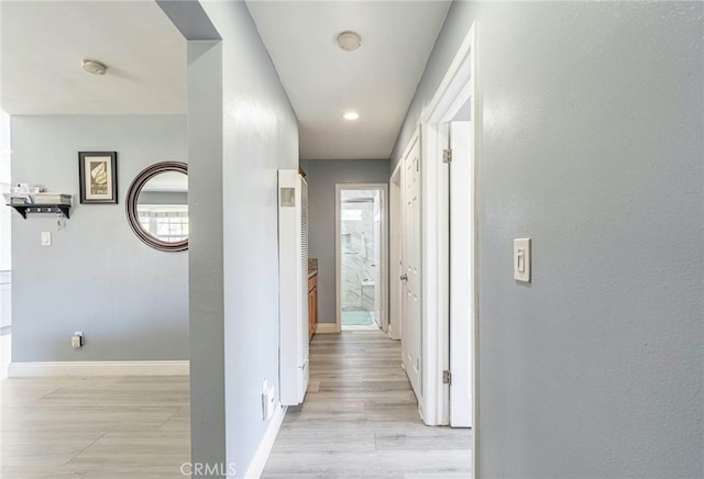 corridor featuring light wood-type flooring and a wealth of natural light