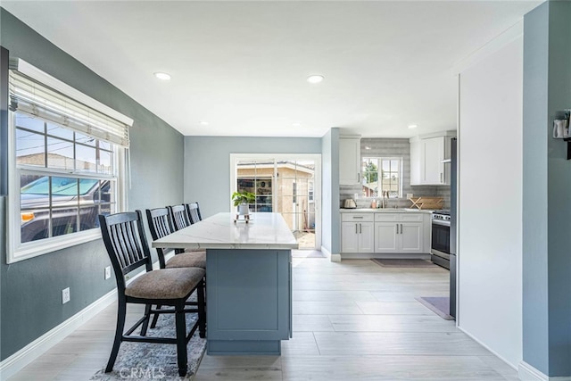 interior space with white cabinets, a breakfast bar area, light hardwood / wood-style floors, and a wealth of natural light