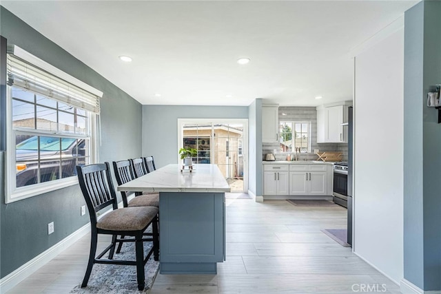 kitchen featuring light wood-type flooring, plenty of natural light, a kitchen bar, and white cabinetry