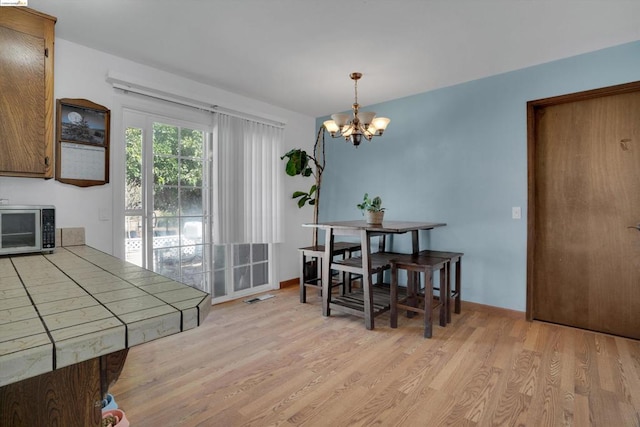 dining space featuring light hardwood / wood-style floors and a chandelier