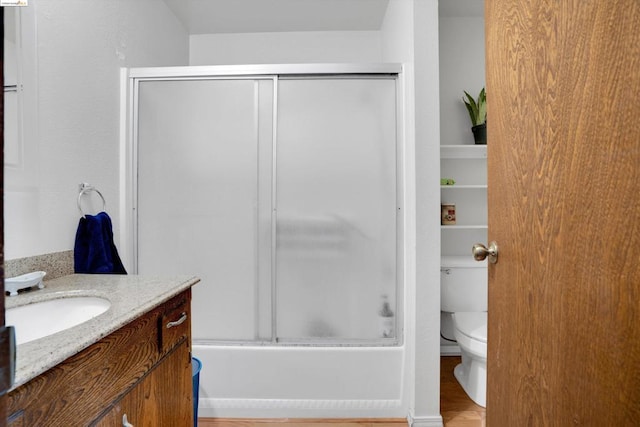 full bathroom featuring bath / shower combo with glass door, vanity, toilet, and hardwood / wood-style flooring