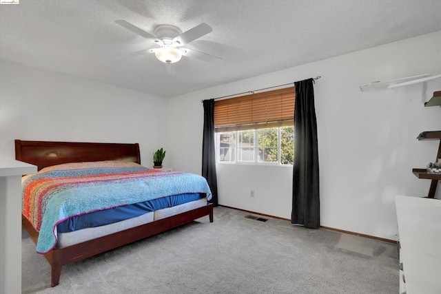 bedroom with a textured ceiling, ceiling fan, and light colored carpet