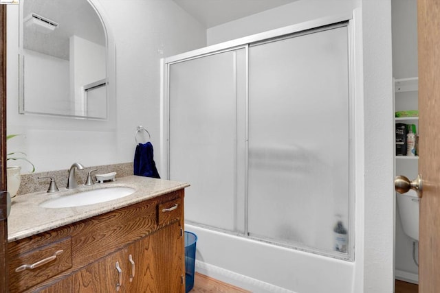 bathroom with hardwood / wood-style flooring, vanity, and enclosed tub / shower combo