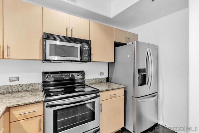 kitchen featuring stainless steel appliances, light brown cabinets, and light stone counters