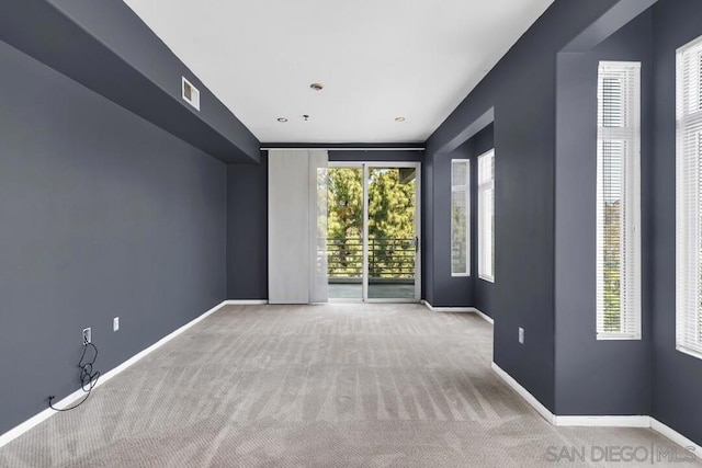 unfurnished room featuring a healthy amount of sunlight and light carpet