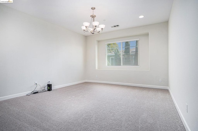 carpeted spare room with an inviting chandelier