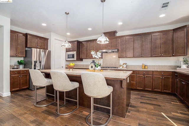 kitchen featuring light stone countertops, stainless steel appliances, dark hardwood / wood-style floors, pendant lighting, and a kitchen island