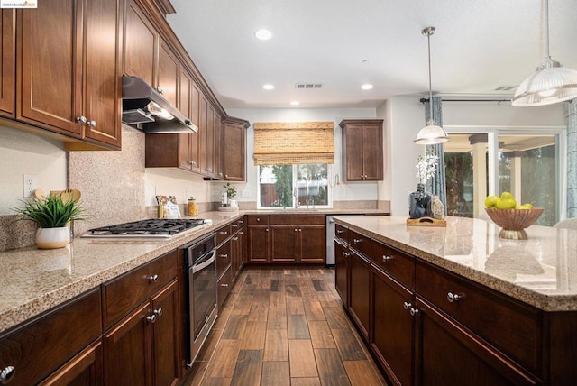 kitchen featuring hanging light fixtures, light stone countertops, dark hardwood / wood-style flooring, and stainless steel appliances