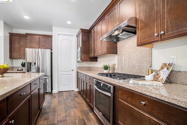 kitchen with light stone countertops, appliances with stainless steel finishes, dark hardwood / wood-style flooring, decorative backsplash, and dark brown cabinetry