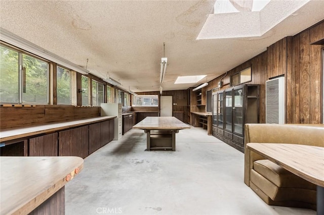 interior space featuring a textured ceiling, a skylight, and wood walls