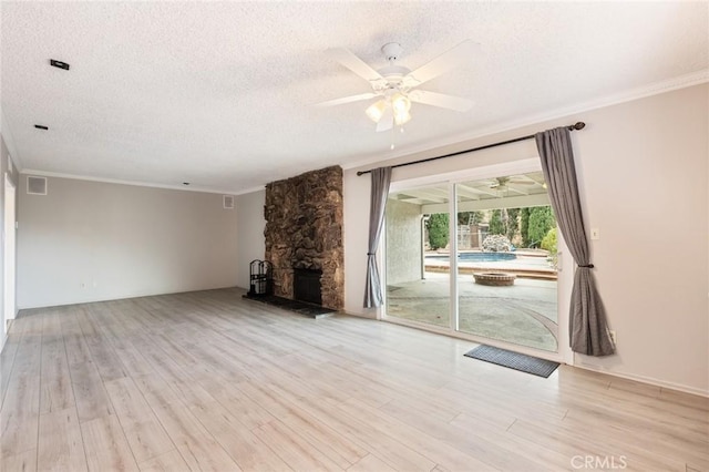 unfurnished living room featuring light hardwood / wood-style floors, a stone fireplace, ornamental molding, and a textured ceiling