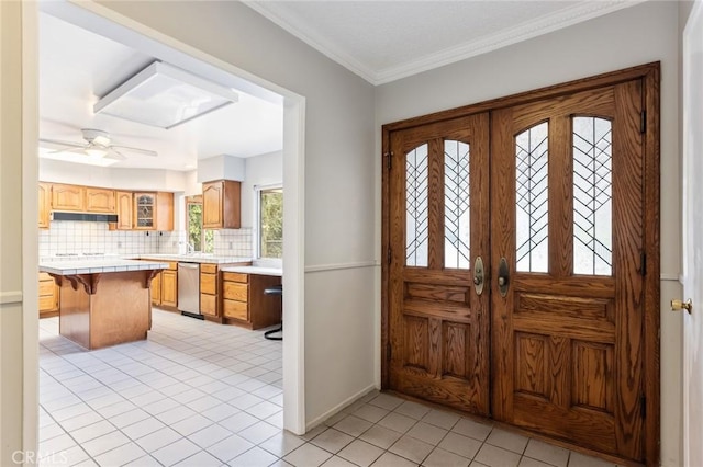 entrance foyer with ceiling fan, french doors, light tile patterned floors, and ornamental molding