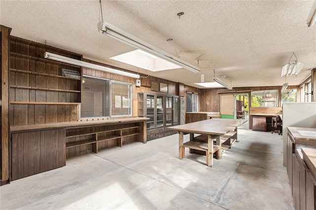 recreation room featuring a skylight, wood walls, and a textured ceiling