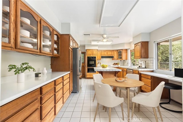 kitchen featuring decorative backsplash, stainless steel appliances, ceiling fan, and light tile patterned flooring