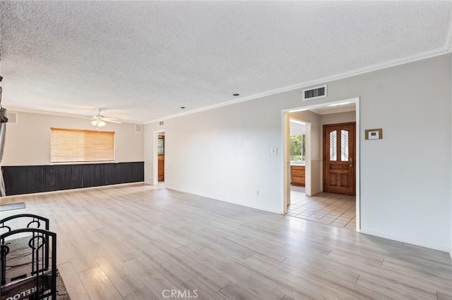 empty room featuring ceiling fan, light hardwood / wood-style flooring, a textured ceiling, and ornamental molding