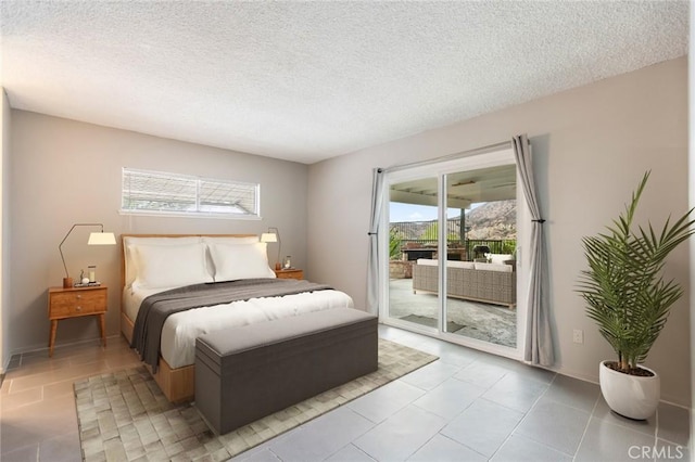 bedroom with a textured ceiling, access to exterior, and multiple windows