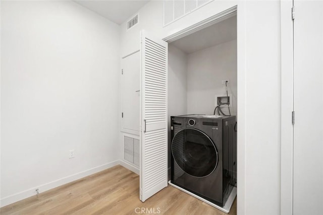 clothes washing area with light hardwood / wood-style flooring and washer / dryer