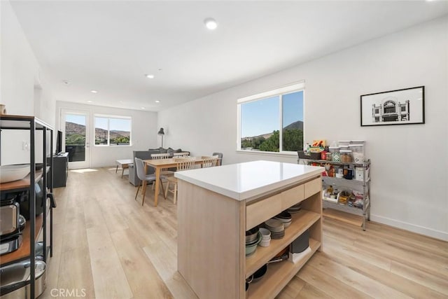 kitchen with light hardwood / wood-style floors, a kitchen island, and light brown cabinets