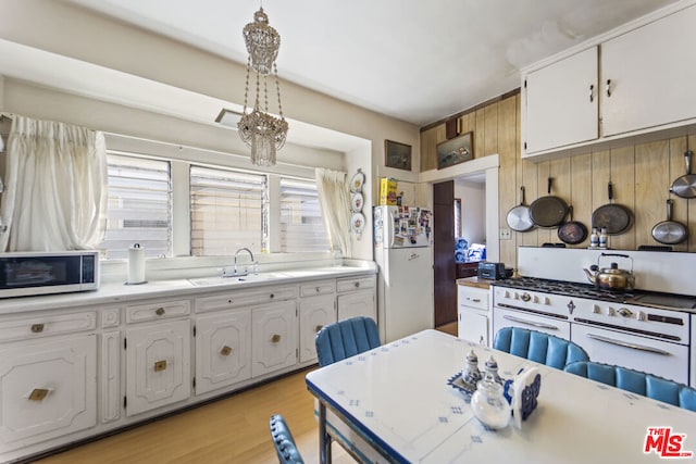 kitchen featuring light hardwood / wood-style floors, white cabinets, white appliances, decorative light fixtures, and sink