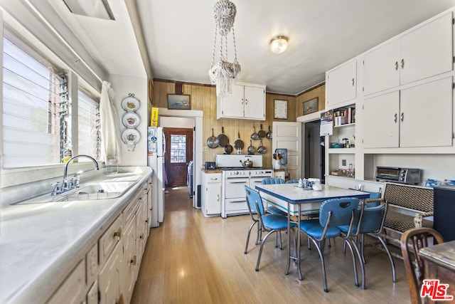 kitchen featuring sink, white appliances, decorative light fixtures, white cabinetry, and light wood-type flooring