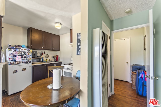 kitchen featuring a textured ceiling, white appliances, dark brown cabinets, and dark hardwood / wood-style flooring