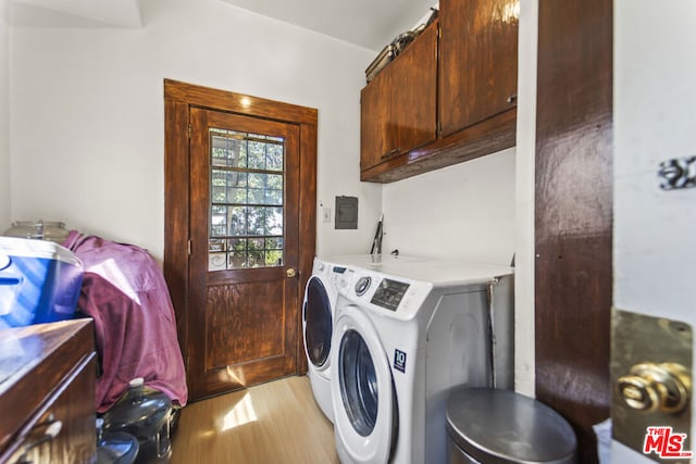 clothes washing area with light wood-type flooring, independent washer and dryer, and cabinets