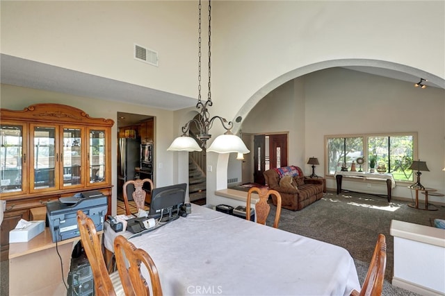 dining space featuring an inviting chandelier, carpet, and high vaulted ceiling