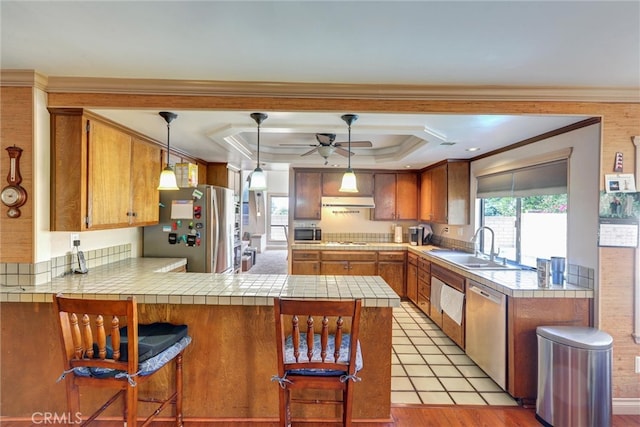 kitchen featuring appliances with stainless steel finishes, light wood-type flooring, kitchen peninsula, hanging light fixtures, and a breakfast bar