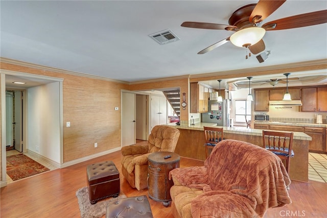 living room with crown molding, light wood-type flooring, and ceiling fan