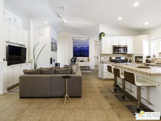 tiled living room with vaulted ceiling and ceiling fan