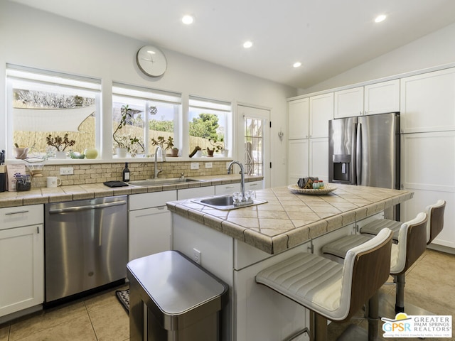 kitchen featuring stainless steel appliances, tile counters, and white cabinetry