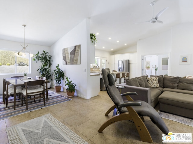 tiled living room featuring ceiling fan with notable chandelier, plenty of natural light, and vaulted ceiling