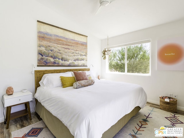 bedroom with hardwood / wood-style flooring and ceiling fan with notable chandelier