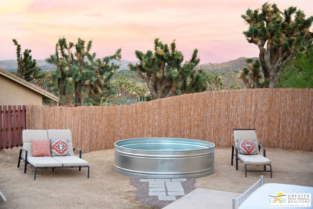 patio terrace at dusk with a hot tub and a mountain view