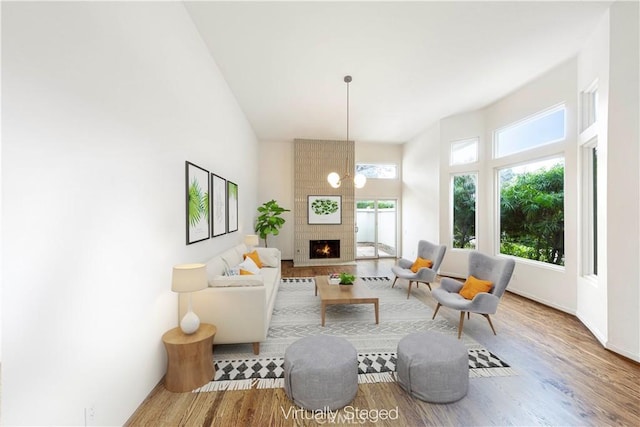 living room with a fireplace, wood-type flooring, and a high ceiling