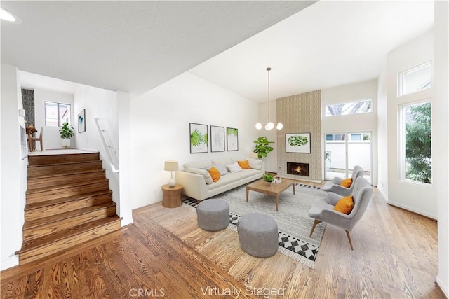 living room featuring a fireplace, a chandelier, and light wood-type flooring